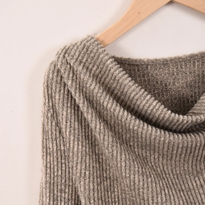 Dettaglio di maglione grigio in maglia a coste con tessuto morbido su gruccia in legno