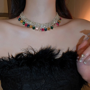 Détail de cristaux rectangulaires colorés sur un collier ras du cou doré à franges