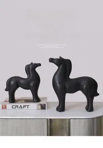 Detail view of two matte black ceramic horse sculptures on a marble surface decor