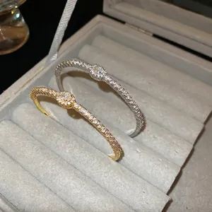 Gold and silver plated open bracelets with oval cubic zirconia on a velvet jewelry stand