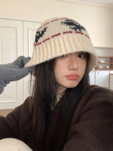 Close-up of beige knit bucket hat with pattern worn with sweater in winter scene
