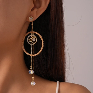 Detail of golden tassel earrings with woven ring, star charms and iridescent beads