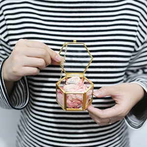 Hexagonal transparent glass wedding ring box with gold frame and preserved pink flowers