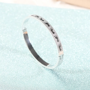 Close-up of titanium steel bangle showing black footprints pattern on polished silver surface