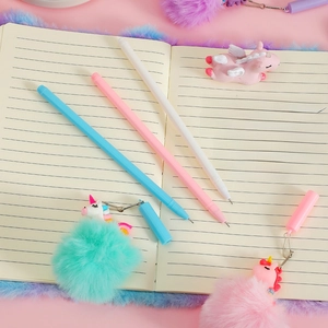 Detailed view of three unicorn pens with fluffy pom-poms on a notebook stationery set