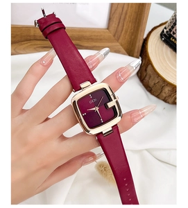 Gros plan d'une montre carrée vintage en cuir bordeaux avec boîtier doré au poignet