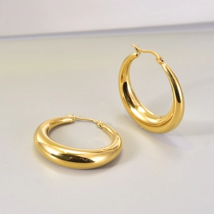 Primer plano de pendientes de aro de media luna huecos bañados en oro 18K con brillo metálico