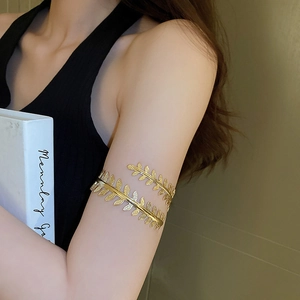 Close-up of golden leaf arm cuff bracelet with intricate wheat ear textures on a model
