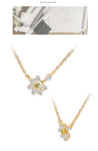Detail of flower pendant necklace featuring green gemstone and marquise zirconia petals