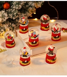 Close-up of Christmas snow globe with Santa and reindeer on a red musical base