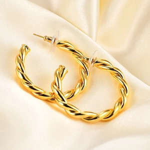 Minimalist 18K gold-plated twisted hoop earrings on soft cream silk fabric background