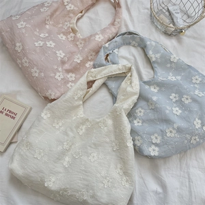 Close-up of intricate floral embroidery details on soft pastel canvas tote bags
