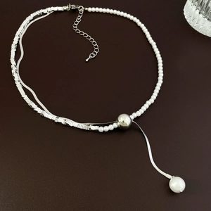 Detail of a silver-toned chain with pearls and a large pearl pendant on leather background