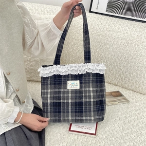 Detail of blue plaid tote bag with delicate white lace trim and cute cartoon patch
