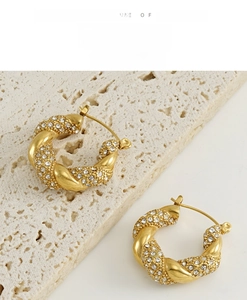 Macro detail of 18K gold plated twist hoop earrings with pavé white rhinestones