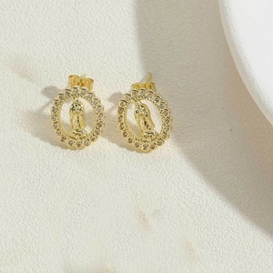 Detail view of oval gold earrings with Virgin Mary relief and sparkling zircon halo