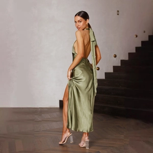 Detail of sage green satin maxi dress showing halter neck with a bow and high slit design