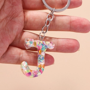Macro shot of letter J resin keychain with colorful sequins and silver metal ring