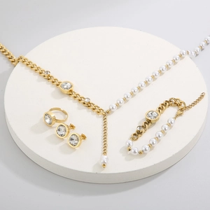 Detail of jewelry set with gold chains, pearls and square cubic zirconia stones