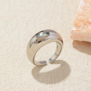Macro detail of polished silver irregular dome ring on natural textured stone background