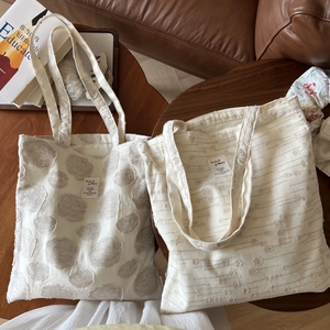 Detailed macro view of textured cream cotton linen tote bags with jacquard patterns