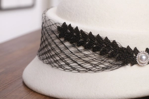 Détail d'un béret en laine avec dentelle noire, perles et décorations en strass étincelants
