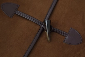 Dettaglio cappotto in pelle scamosciata marrone con alamari scuri e cuciture