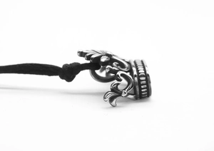 Macro shot of punk style steel crown pendant with intricate floral details on black cord