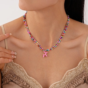 Détail d'un collier de perles colorées double couche avec pendentif chien ballon rose au cou