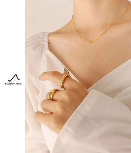 Detail of 18K gold-plated stainless steel heart necklace and rings on model
