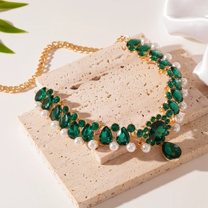 Macro view of emerald green stones and imitation pearls on a gold-plated flower choker