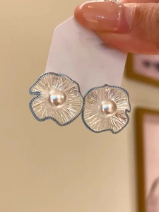Detail of silver wavy flower earrings with blue texture and central white pearl