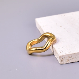 Minimalist golden wavy stainless steel ring with K engraving on a beige stone