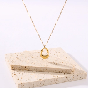18K gold plated hollow oval stainless steel necklace on beige stone, minimalist style