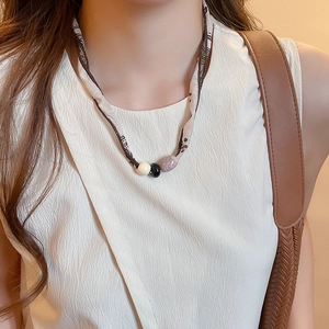 Close-up of silk scarf necklace with ivory, black, and marble-textured beads