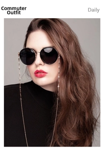 Detail of gold metal glasses chain with small cross charms on black round sunglasses