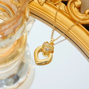 Macro shot of gold heart necklace with micro-paved cubic zirconia on mirrored surface