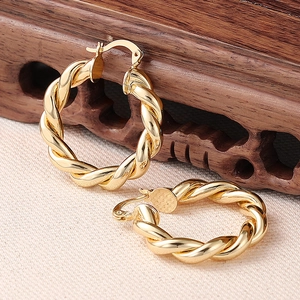 Detail von goldenen gedrehten Creolen auf Leinen mit einem Vintage-Holzsockel
