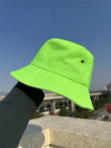 Detail view of neon green cotton bucket hat fabric and texture against a blue sky