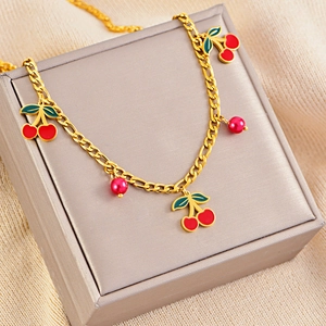 Detailed close-up of a gold chain necklace with red cherry charms and deep red pearls