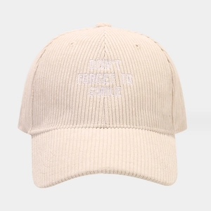 Detailed close-up of 'DON'T FORGET TO SMILE' white embroidery on corduroy baseball cap