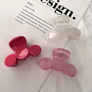 Three floral hair claws in pink and clear plastic on an open magazine page