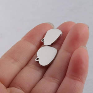 Close-up of two mirror polished heart-shaped stainless steel charms on fingertips