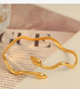 Macro detail of golden snake-shaped stainless steel bracelet with polished finish