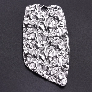 Macro view of irregular silver 304 stainless steel pendant with hammered metal texture