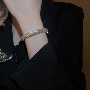 Detail of pavé-set crystals on gold-toned textured bangle worn by a model