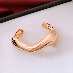 Macro view of a gold irregular open bangle with heavy fluid design and high polish finish