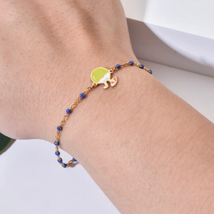 Golden chain bracelet with blue beads and a tropical coconut drink pendant on wrist