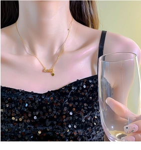 Detailed view of a gold LOVE letter necklace with heart pendant on a model in evening wear