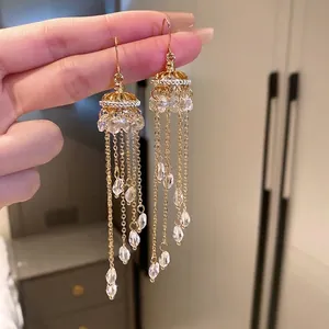 Detailed close-up of golden tassel earrings featuring delicate crystal water-drop pendants